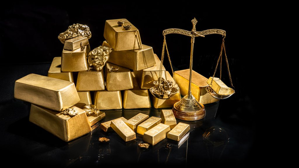 Goldbarren auf einem Haufen mit Goldwaage davor