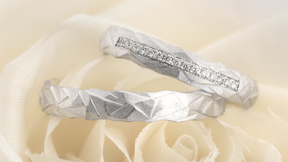 Paar Eheringe in Weißgold mit Struktur und Diamanten auf dem Damenring