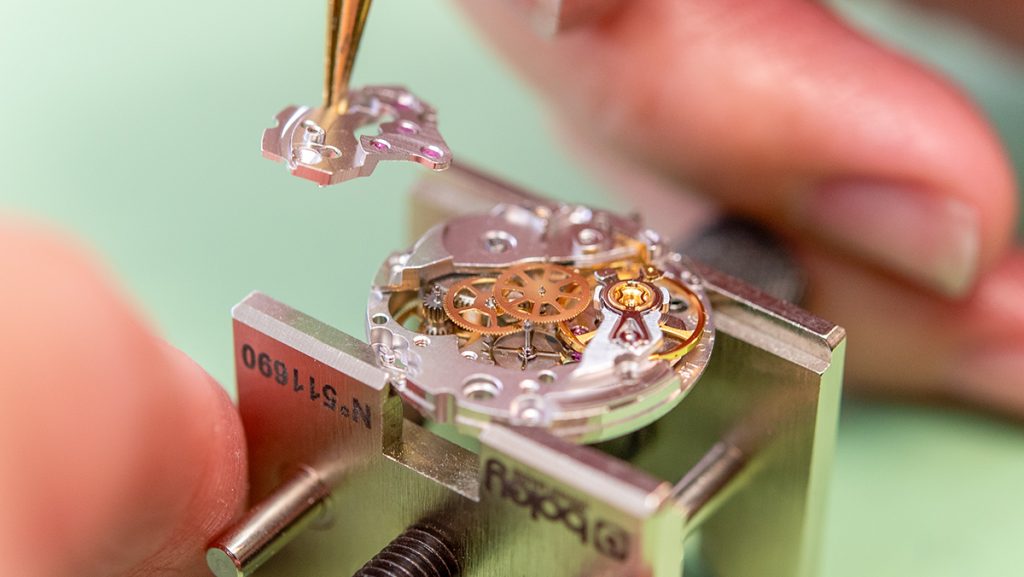 Uhrmacher zerlegt Uhr in Einzelteile zur Revision