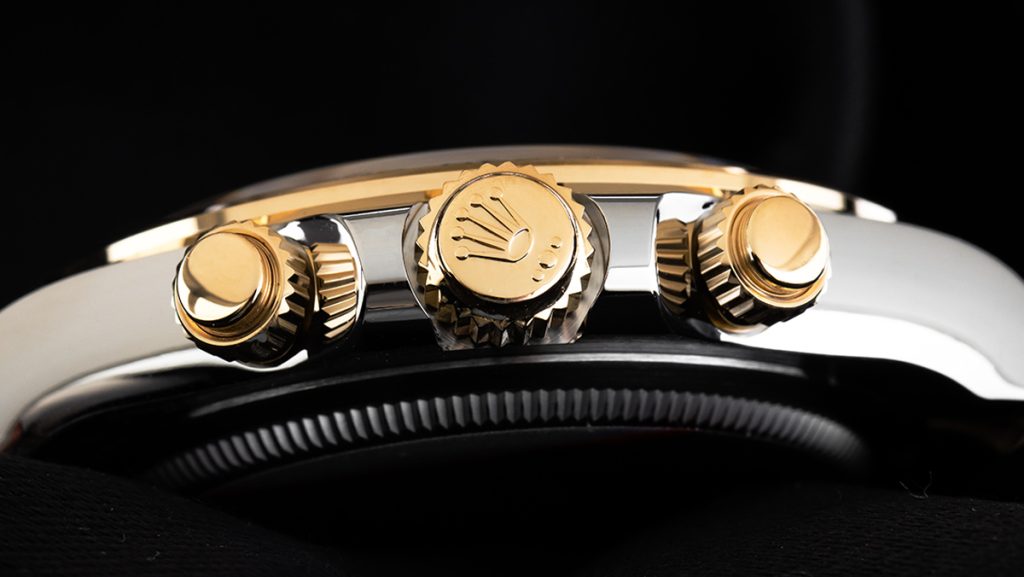 Nahaufnahme von der Seite einer Rolex Daytona mit goldener Krone und Drückern